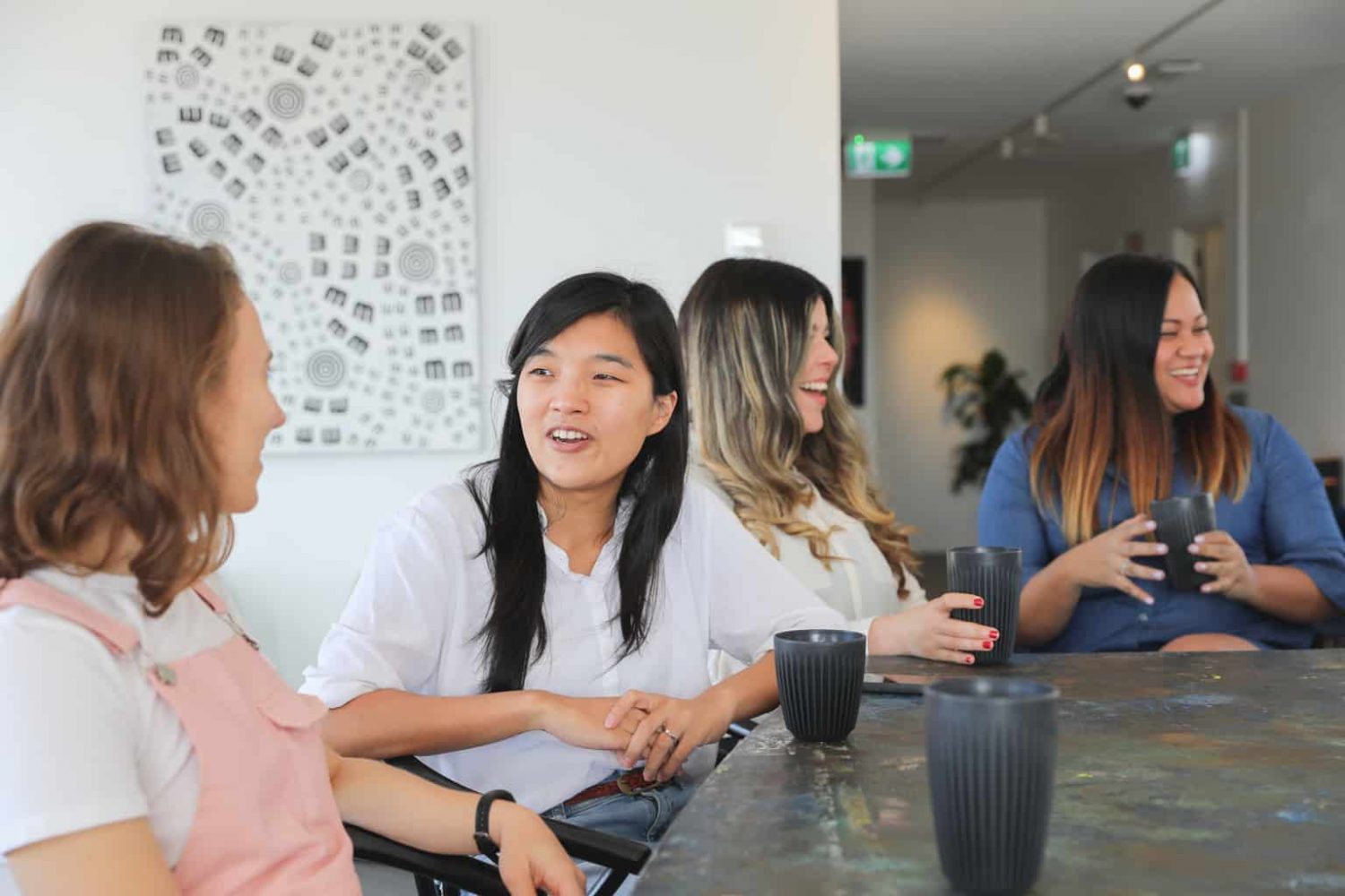 Canva - Women talking over coffee in the office